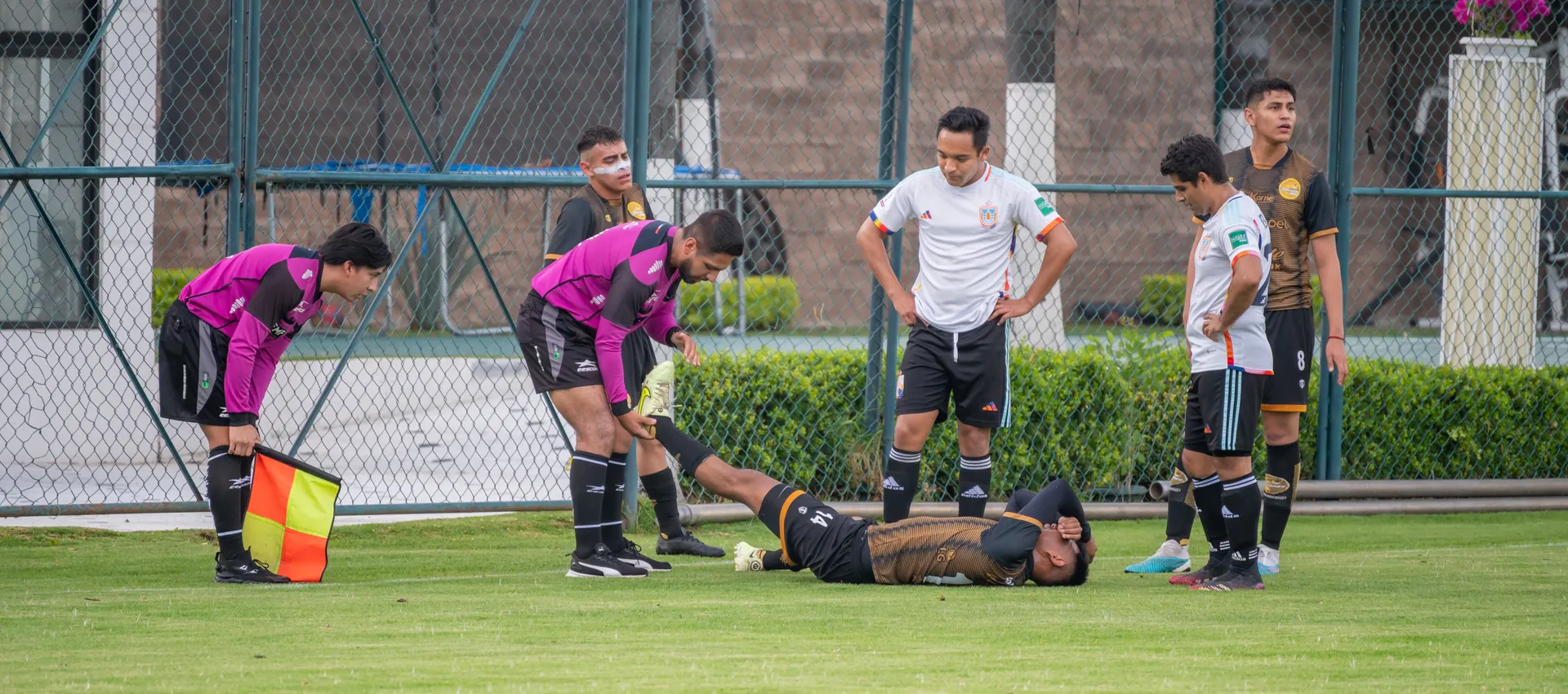 An injured player down in pain on the field as teammates and staff attend to him